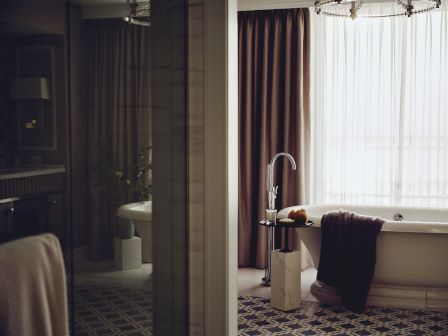 Elegant bathroom with a bathtub, towel, sink, and drapes.