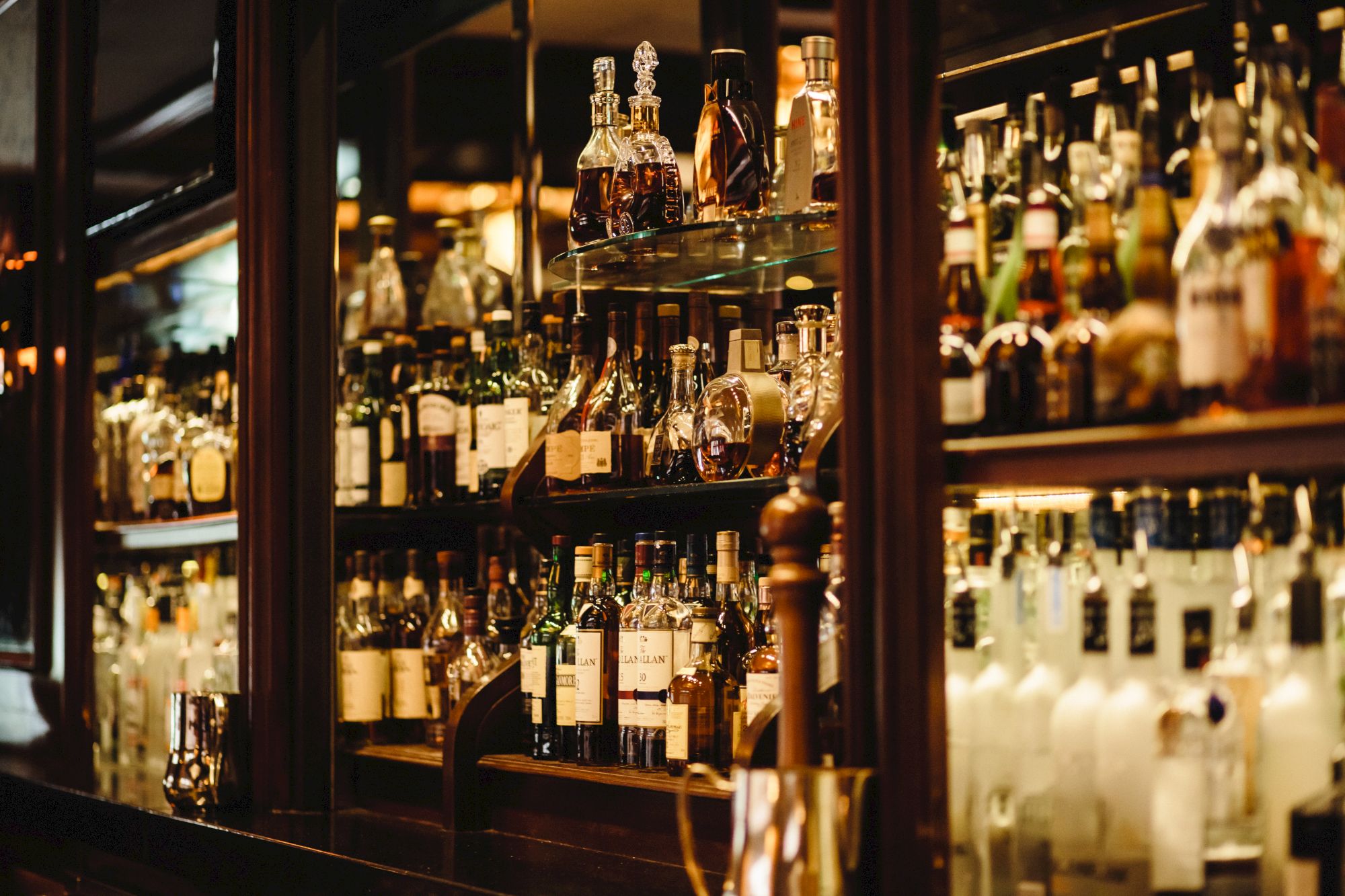 An array of various liquor bottles on illuminated shelves in a bar.