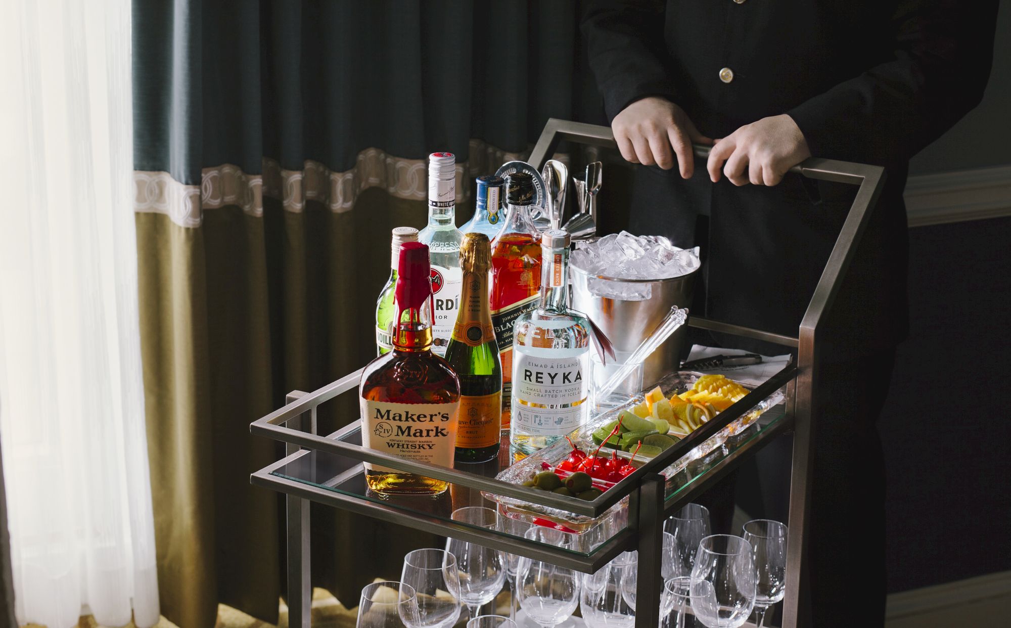 A bar cart with various bottles, ice bucket, and garnishes.