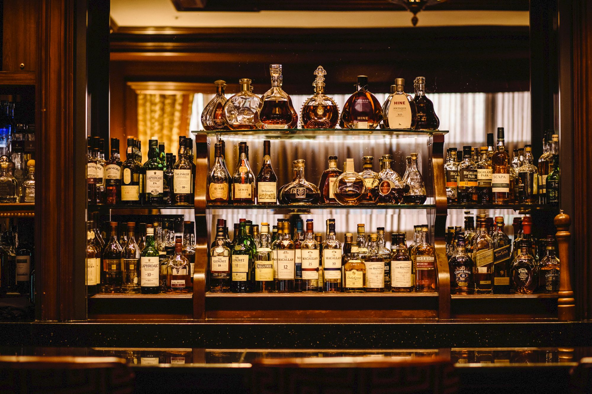 An array of various liquor bottles displayed on shelves behind a bar.