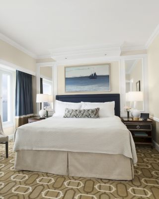 Elegant room with a large bed, artwork, and waterfront view.