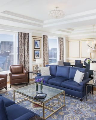Luxurious room with blue sofas, chairs, chandelier, and city view.