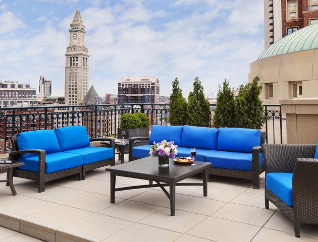Outdoor patio with blue sofas, city skyline, and a clock tower in the background