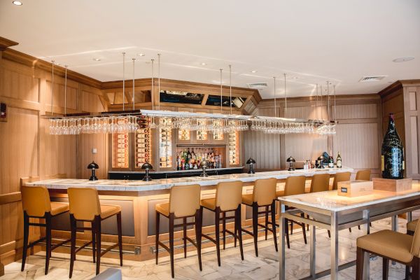 An elegant bar area with stools, pendant lights, and a well-stocked counter