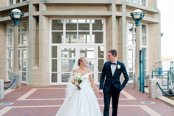 A couple in wedding attire is posing in front of an elegant building.