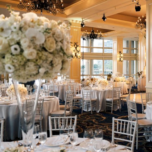 Elegant banquet hall set for an event with floral centerpieces, round tables,