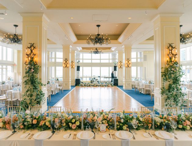Elegant banquet hall with floral decorations, chandeliers, and dance floor set