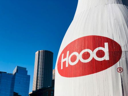 A large Hood milk bottle structure with city buildings in the background.