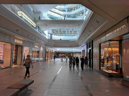 Indoor shopping mall with luxury stores and shoppers walking.