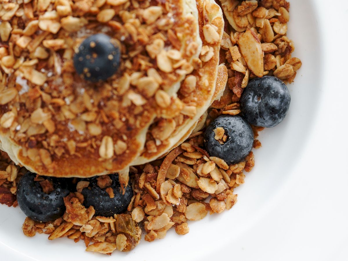 Pancakes with granola and blueberries on a plate.