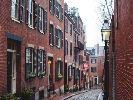 Cobblestone street with historic red brick buildings and street lamps.