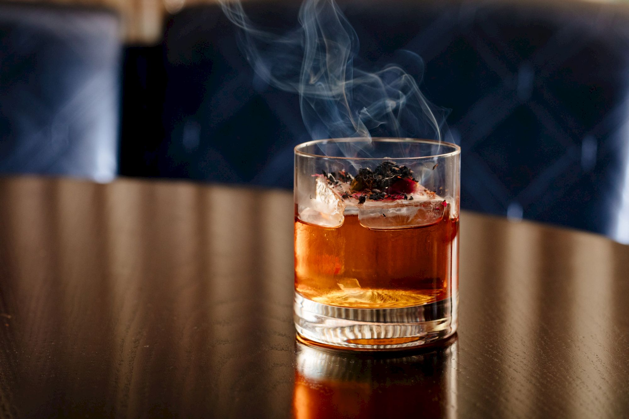 A smoky cocktail with ice on a table, emitting a pleasant aroma.