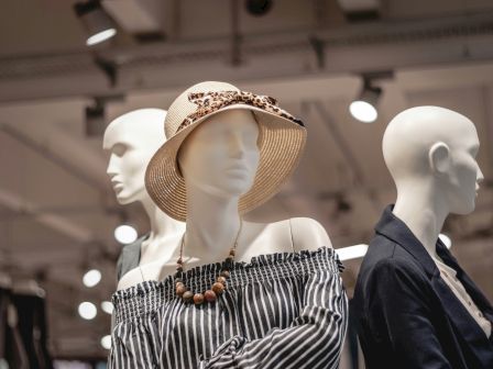 Three mannequins wearing stylish clothes and accessories are displayed in a store.