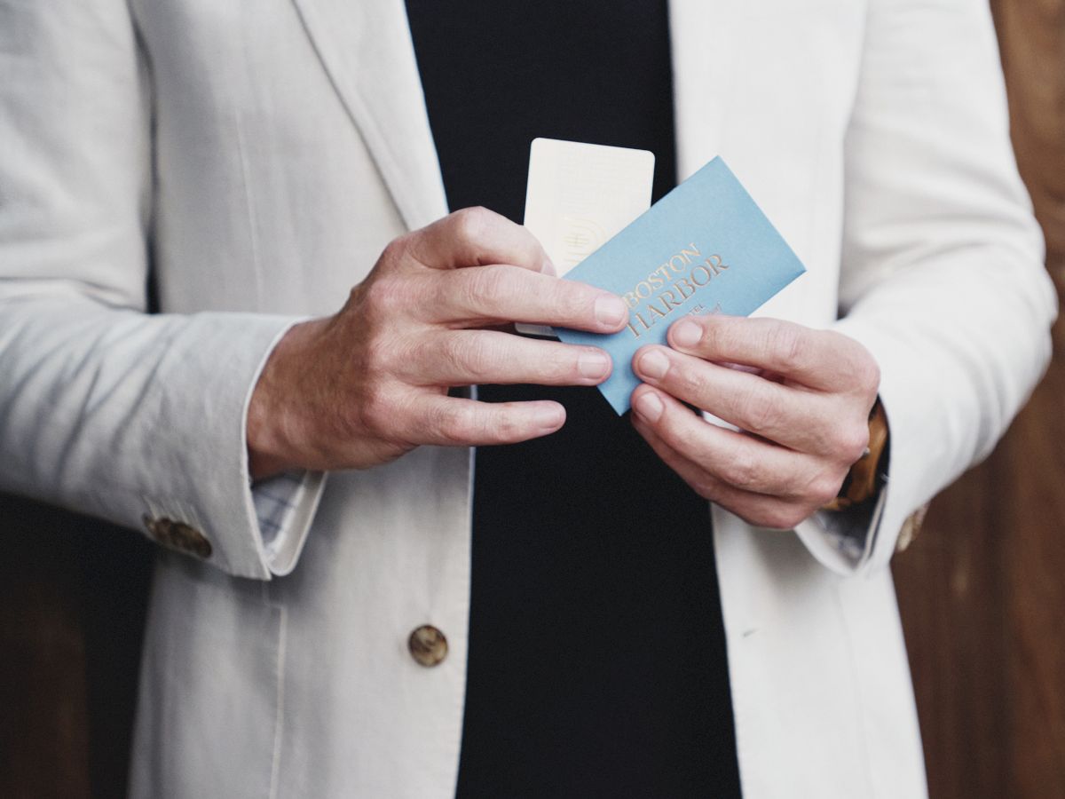 A person in a blazer is holding a card and a phone.