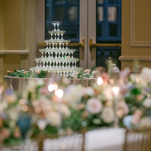 Elegant event setting with floral decor and a tiered cake in the background.
