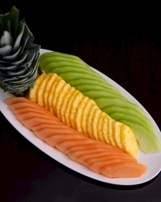 A plate with sliced fruits: pineapple, mango, kiwi, and papaya