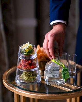 A person serves drinks and appetizers on a tray.
