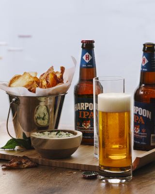 Beer bottles, a glass of beer, chips, and dip are visible on a