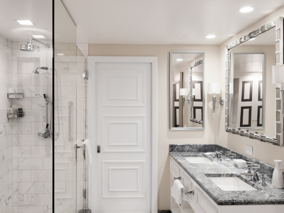 A modern bathroom with a glass shower, vanity sink, towels, and a framed