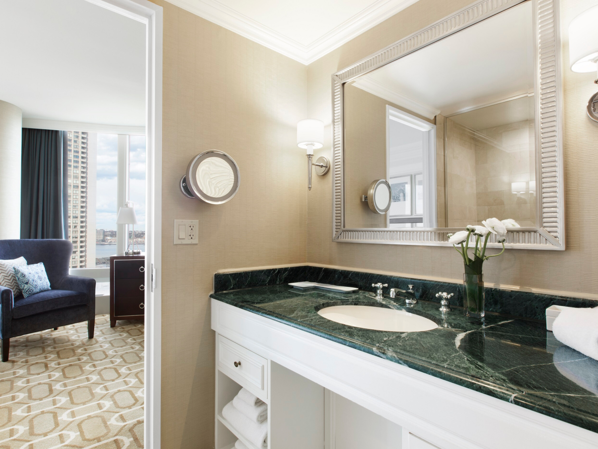 Elegant bathroom with marble countertop and adjacent room glimpse.