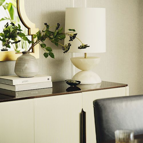 Elegant interior with a table lamp, books, and plant on a table.