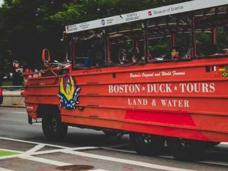 A Boston Duck Tour amphibious vehicle on a road with passengers.