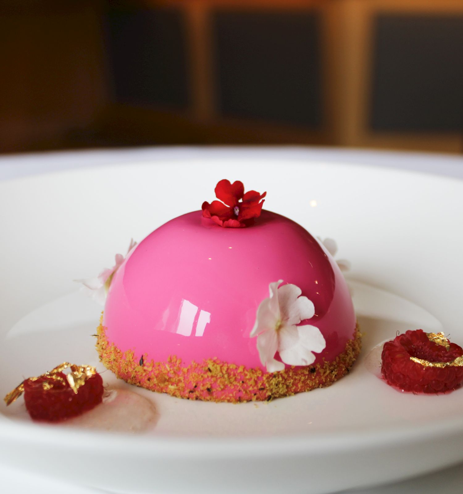 Elegant pink dessert with delicate flowers on a white plate.