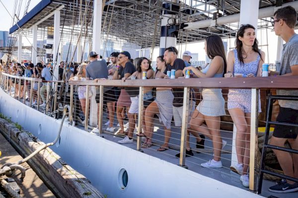 People standing on a dock near a boat, enjoying a sunny day.