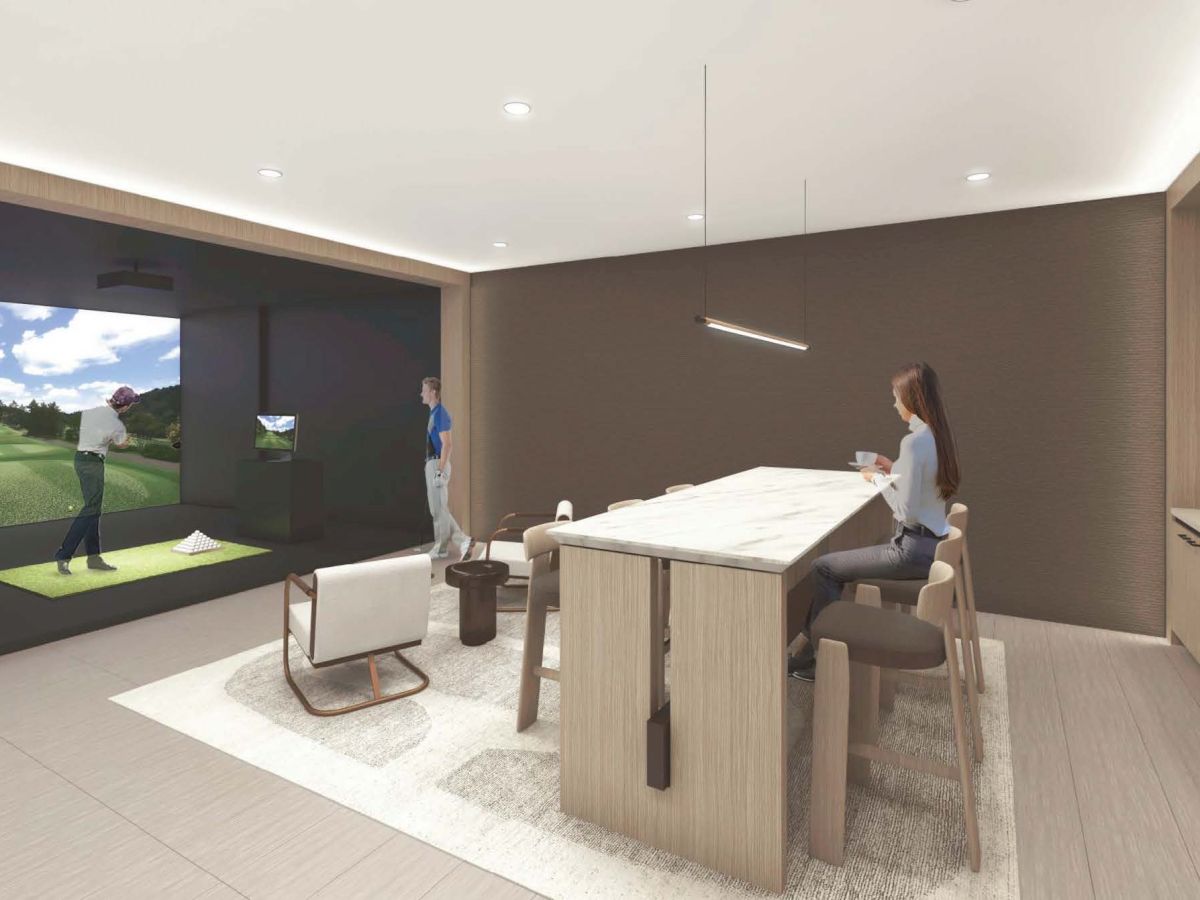 A modern indoor golf simulation room with people playing and watching, featuring a golf simulator screen, seating area, and a kitchen counter.